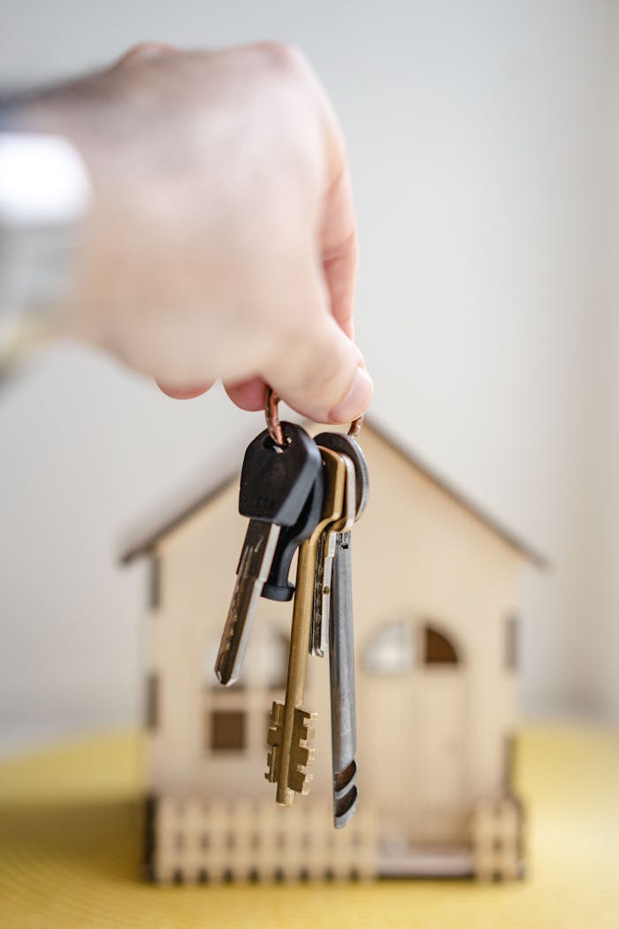 Crafting Captivating Headlines: Your awesome post title goes here Close-up of a hand holding keys with a miniature wooden house in the background, symbolizing real estate investment.